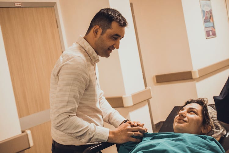 Man Comforting Woman Lying On Bed In Hospital