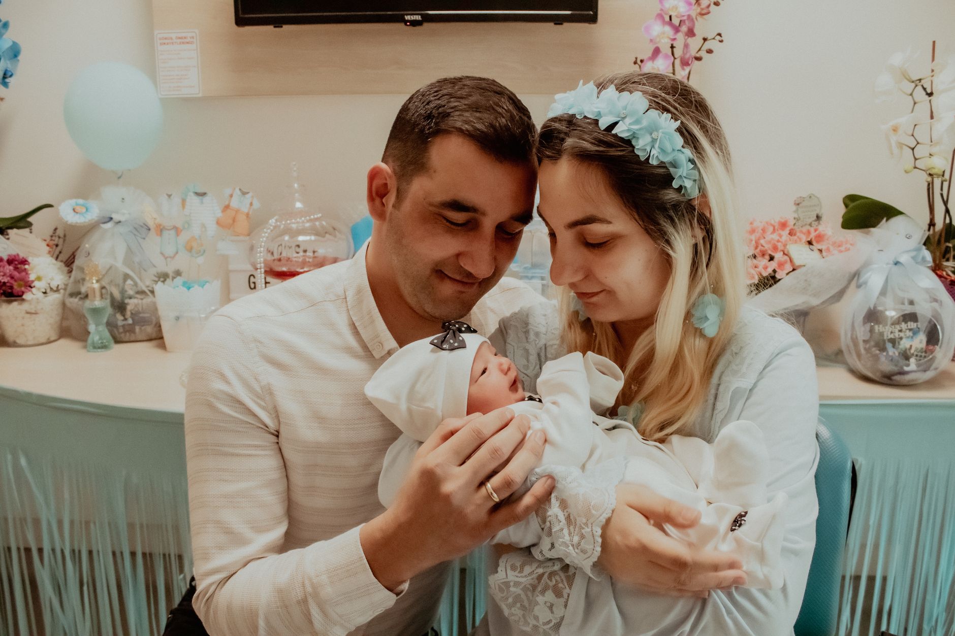 A loving couple embracing their newborn baby at an indoor baby shower.