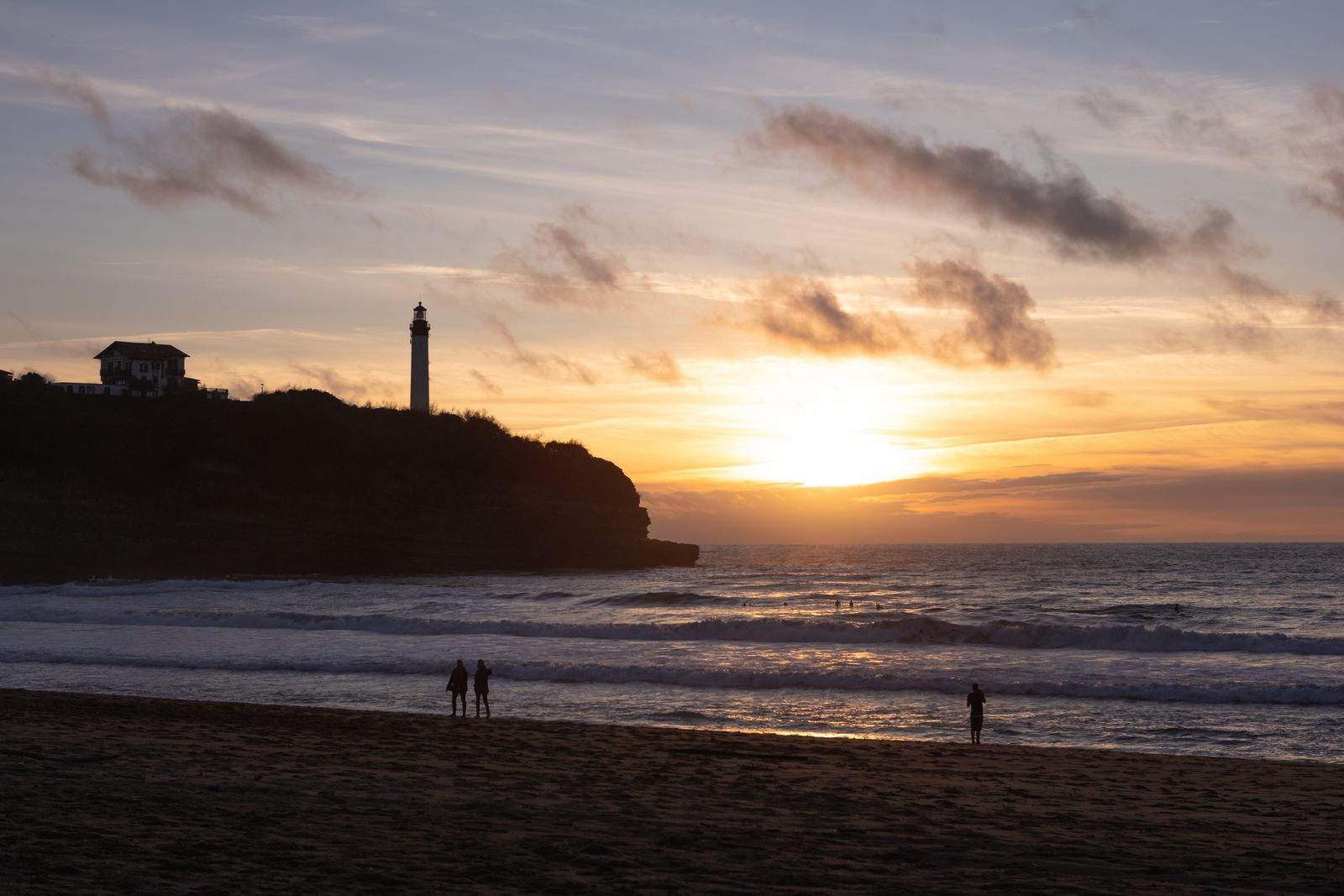 Golden sunset over Biarritz beach, the lighthouse on the headland