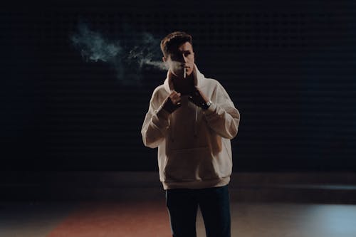 Man in Hoodie Smoking at Night