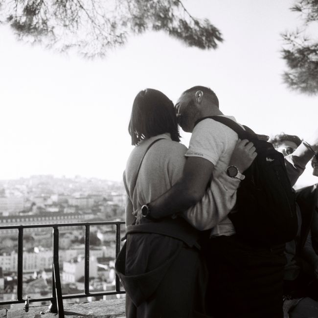 A couple shares an intimate moment overlooking the scenic Lisbon skyline.