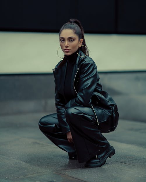 Brunette Woman in Leather Jacket Crouching on Street