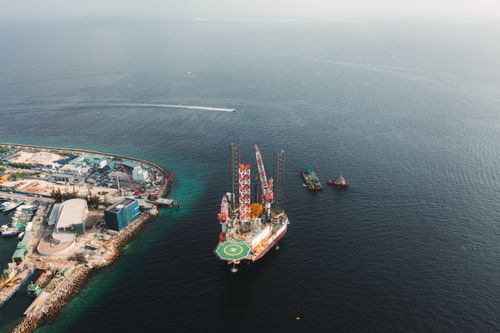 Free Stunning aerial view of an offshore oil production platform with nearby ships and coastline. Stock Photo