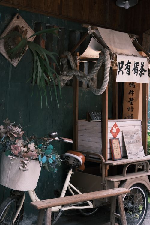 Free Decorative bicycle with flower basket next to a traditional rustic wooden stall with signs. Stock Photo
