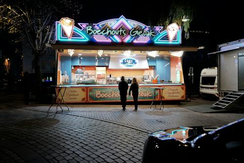 People Standing by Illuminated Food Stand at Night