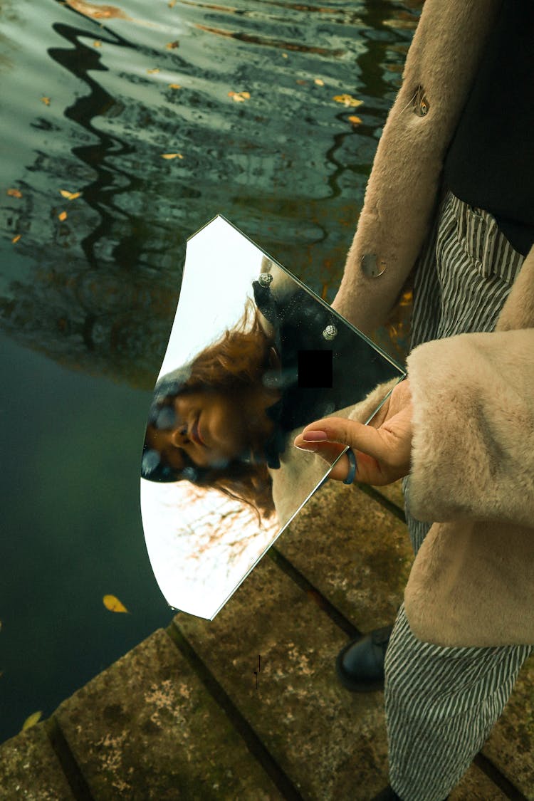 Woman Face Reflection In Mirror Over Water