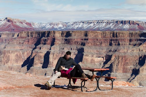 Young Couple Resting on a Bench with Grand Canyon in the Background 