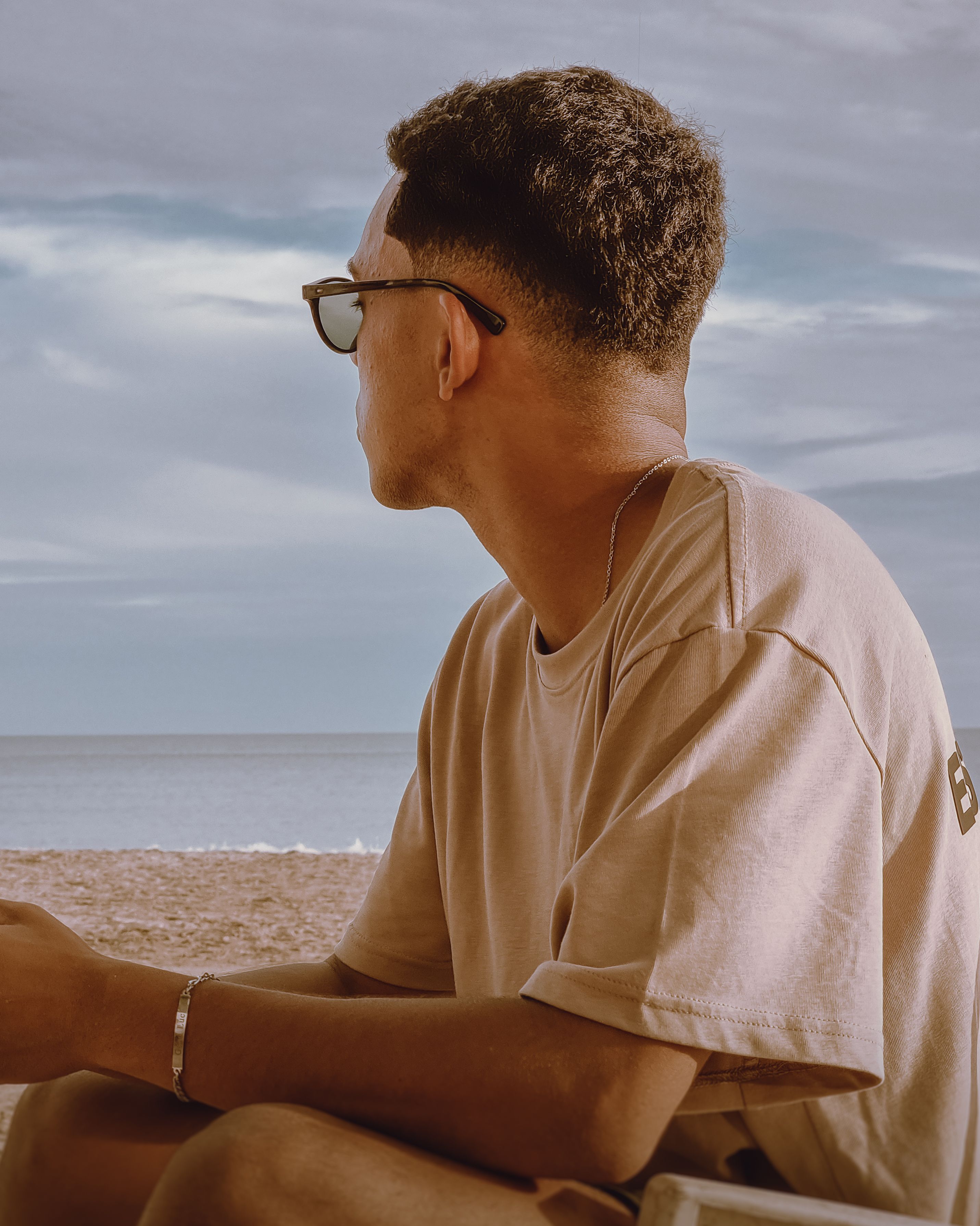 A man in a t-shirt enjoys a peaceful moment on the sandy beach of Guarapari, Brazil.