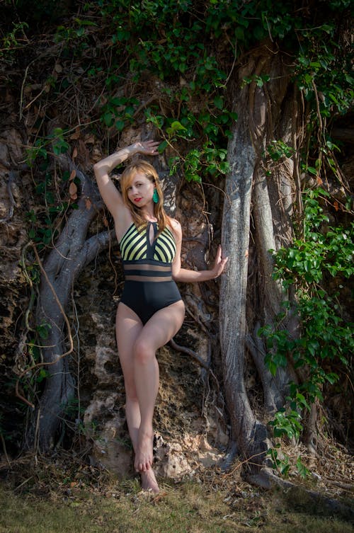 Woman in a Swimming Costume Leaning on a Tree