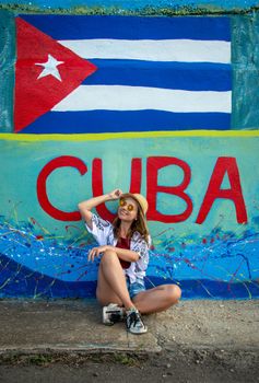 Woman posing by a colorful Cuban mural displaying national pride.