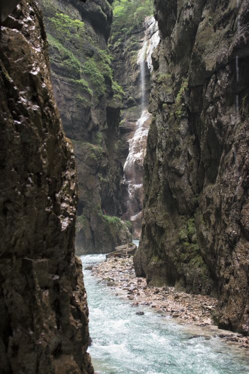 Free Explore this stunning canyon scene featuring a vibrant stream and waterfall cascading down the rocky cliffs. Stock Photo