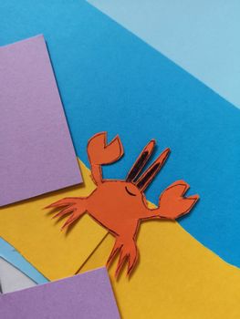 Vibrant paper craft of a cartoon crab on a colorful background, showcasing artistic creativity.