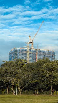 Vertical view of a skyscraper under construction behind lush trees in Taipei, Taiwan.