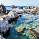 在清澈的海水和明亮的天空下，美丽的岩石海景展现了风景优美的海岸线