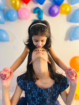 Two young girls having fun at a birthday party with colorful balloons.