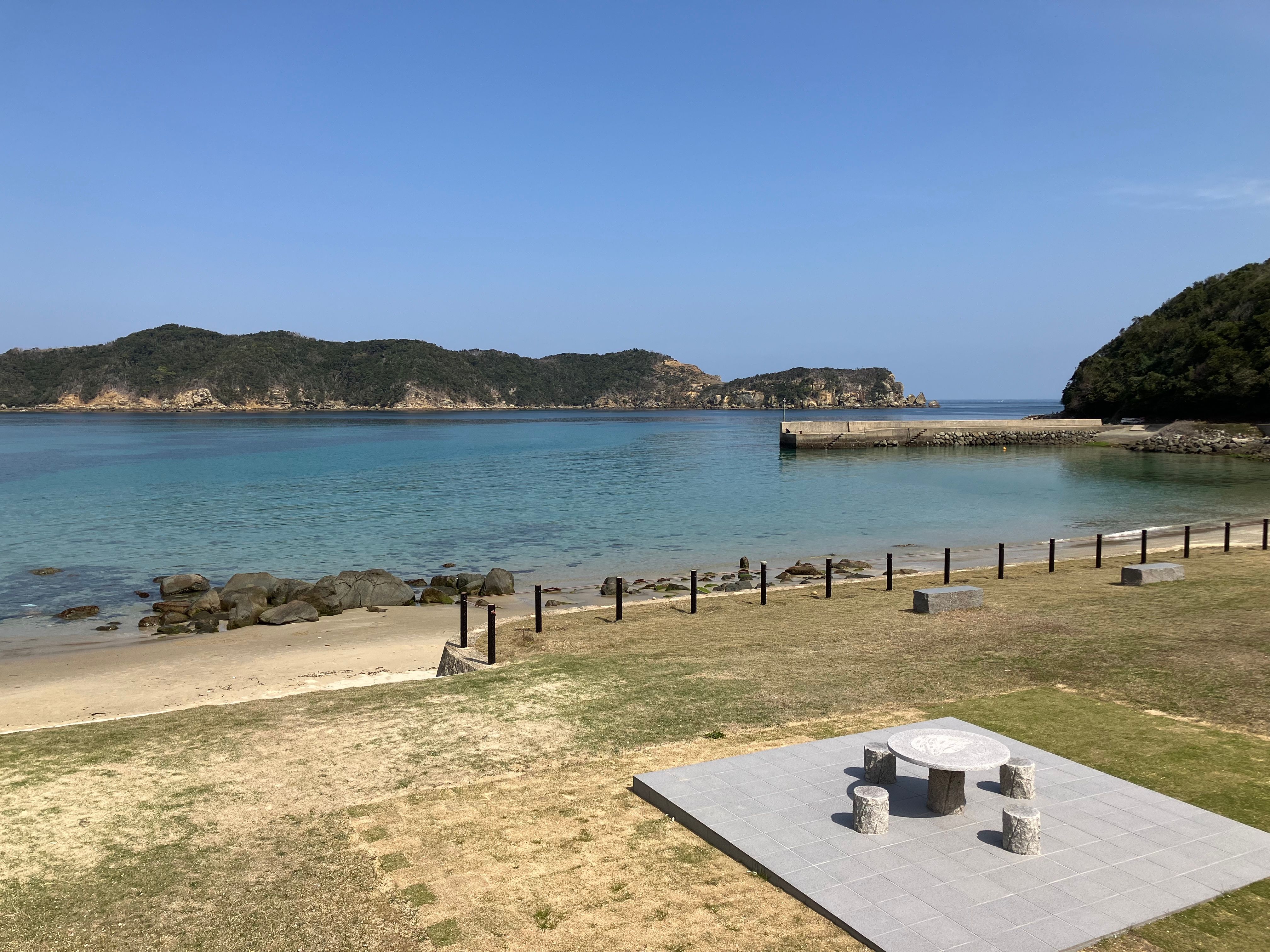 A serene coastal scene with clear waters and a stone seating area, perfect for relaxation.