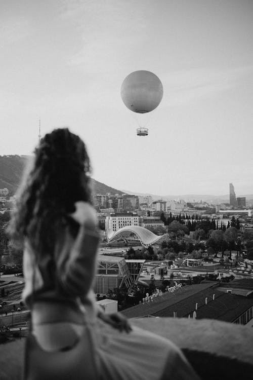 Woman Looking at a Flying Hot Air Balloon 
