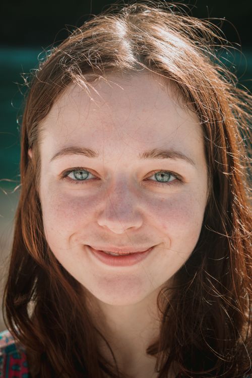 Free Close-up portrait of a woman smiling warmly under sunny outdoor light, capturing a moment of joy. Stock Photo