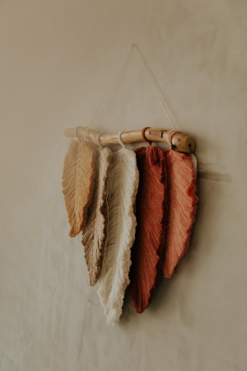 A Rustic Decoration of Yarn Feathers Hanging on a Stick 