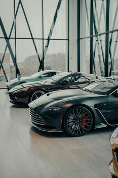 A collection of sleek luxury sports cars displayed in a contemporary showroom with large glass windows.