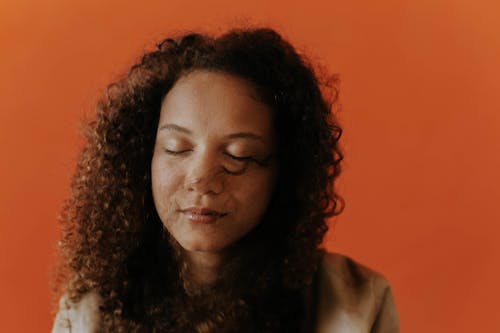 Portrait of a Woman with Curly Hair against Orange Background