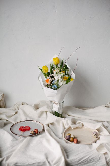 A minimalist still life featuring a bouquet of spring flowers on a textured table.
