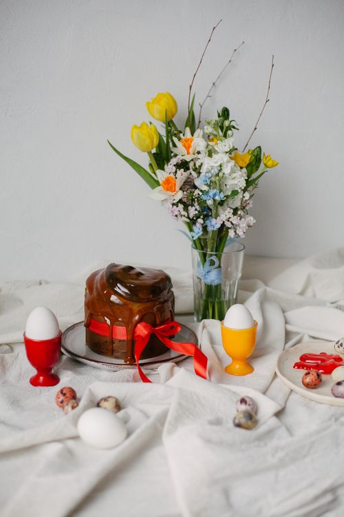 Free A spring-themed table with chocolate cake, flowers, and decorated eggs. Stock Photo