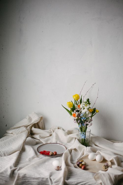 Free A minimalist table setting with colorful spring flowers in a vase, surrounded by Easter eggs and subtle textiles. Stock Photo