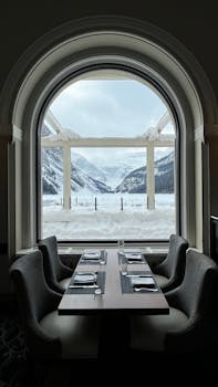 Cozy restaurant with snowy mountain view through an arched window at Lake Louise.