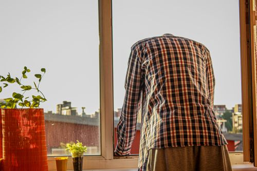 Free A person stands by a window overlooking a city while sunlight streams in. Stock Photo