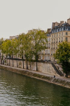 Picturesque view of classic Parisian buildings along the Seine river with trees in autumn colors.