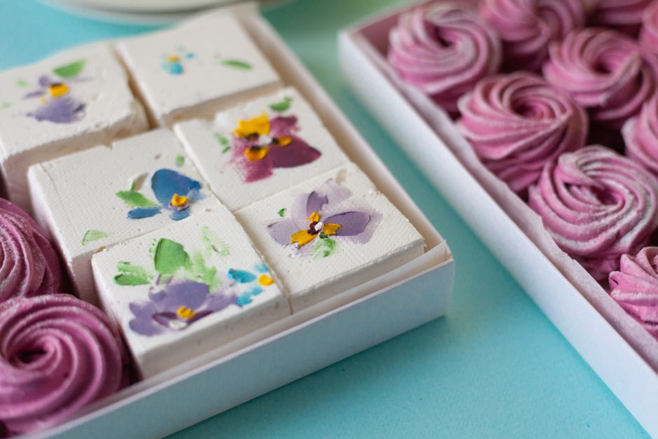 Beautifully arranged floral marshmallows and pink swirled candies in white boxes.