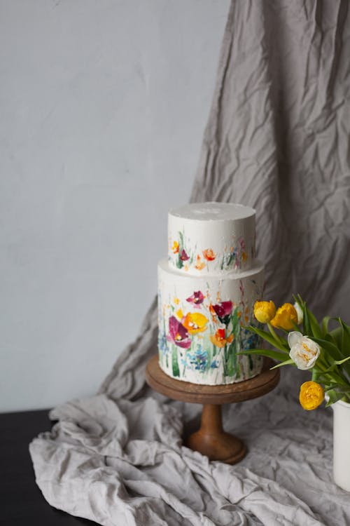 Still Life with a Floral Decorative Cake and Yellow Tulips on a Gray Drape