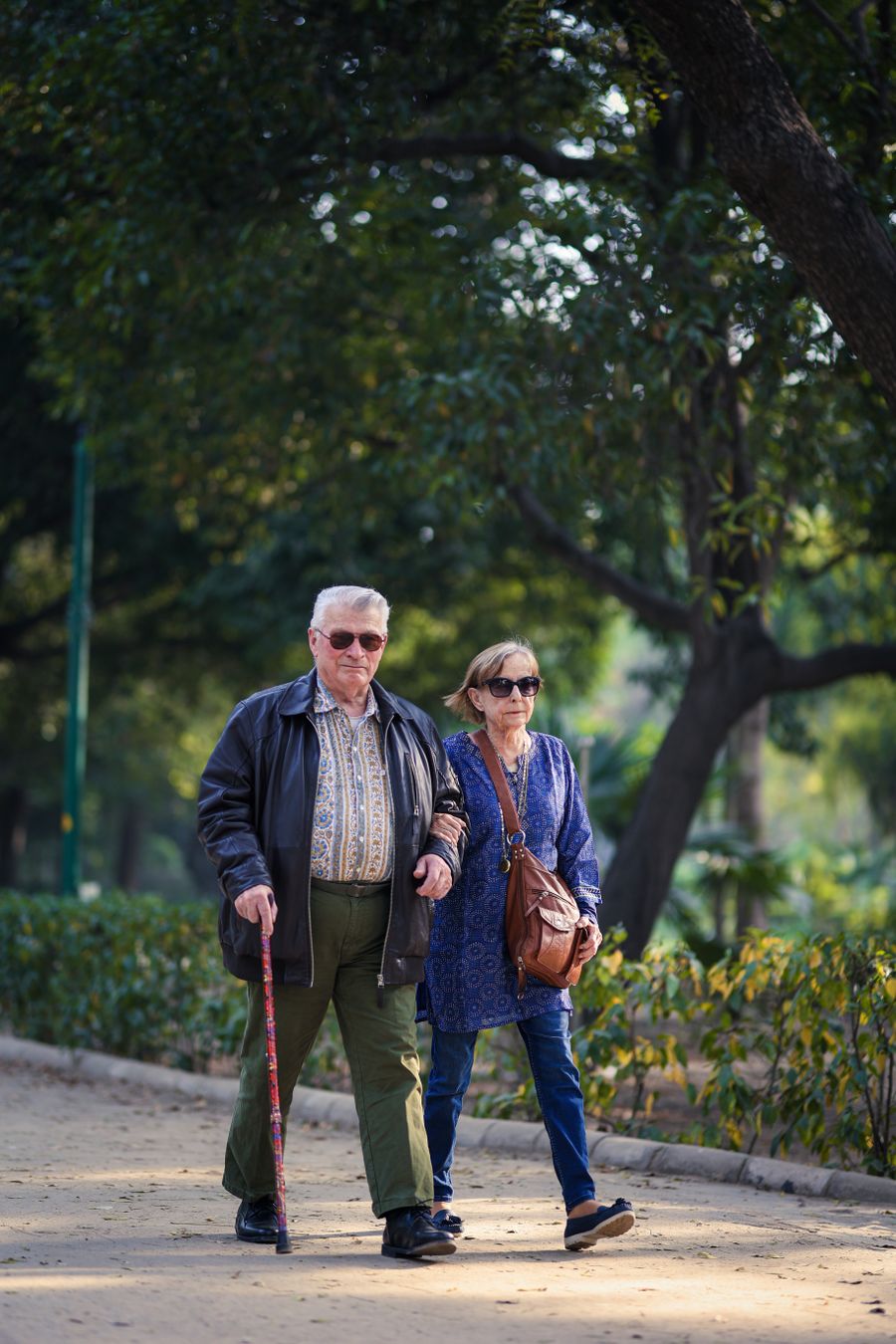 An older couple walking together in a green park