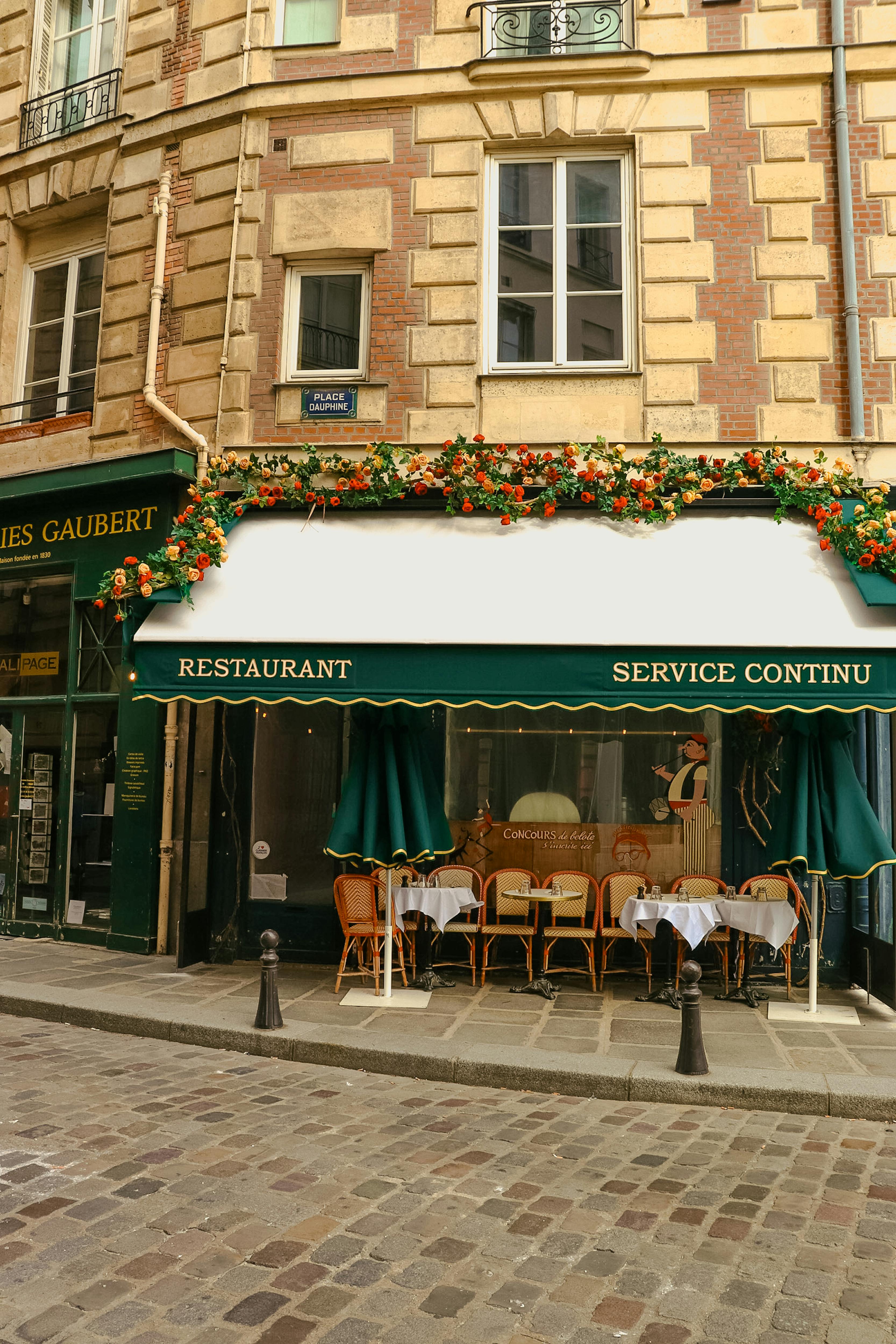 A charming Parisian cafe with colorful awning and outdoor seating in a historic street setting.