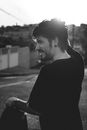 Grayscale Photo of Man Standing While Scratching Head