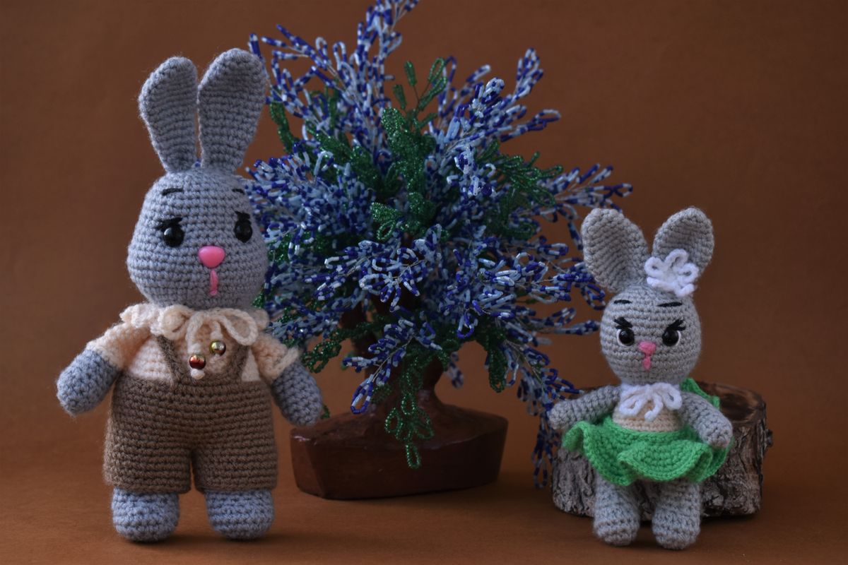 Fertige gehäkelte Amigurumi-Hasen umgeben von Blumen