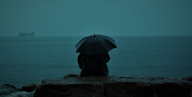 Woman Sitting And Looking At The Sea On A Rainy Day 