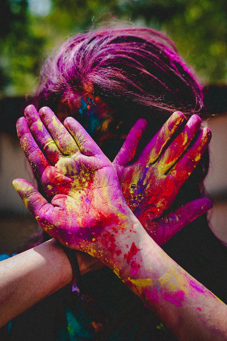 Woman Covered In Colorful Powder After A Holi Festival Covering Her Face With Hands