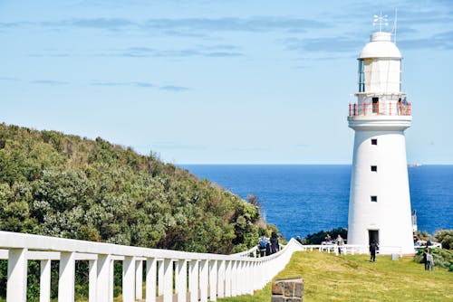 People Standing in Front of White Concrete Lighthouse during Daytime