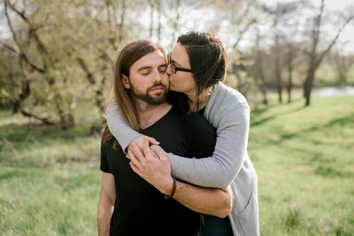 Free A couple shares an affectionate moment outdoors in a sunny park setting. Stock Photo