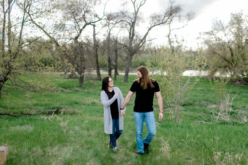 Free A joyful couple walking hand in hand through a lush green meadow in spring, enjoying nature. Stock Photo