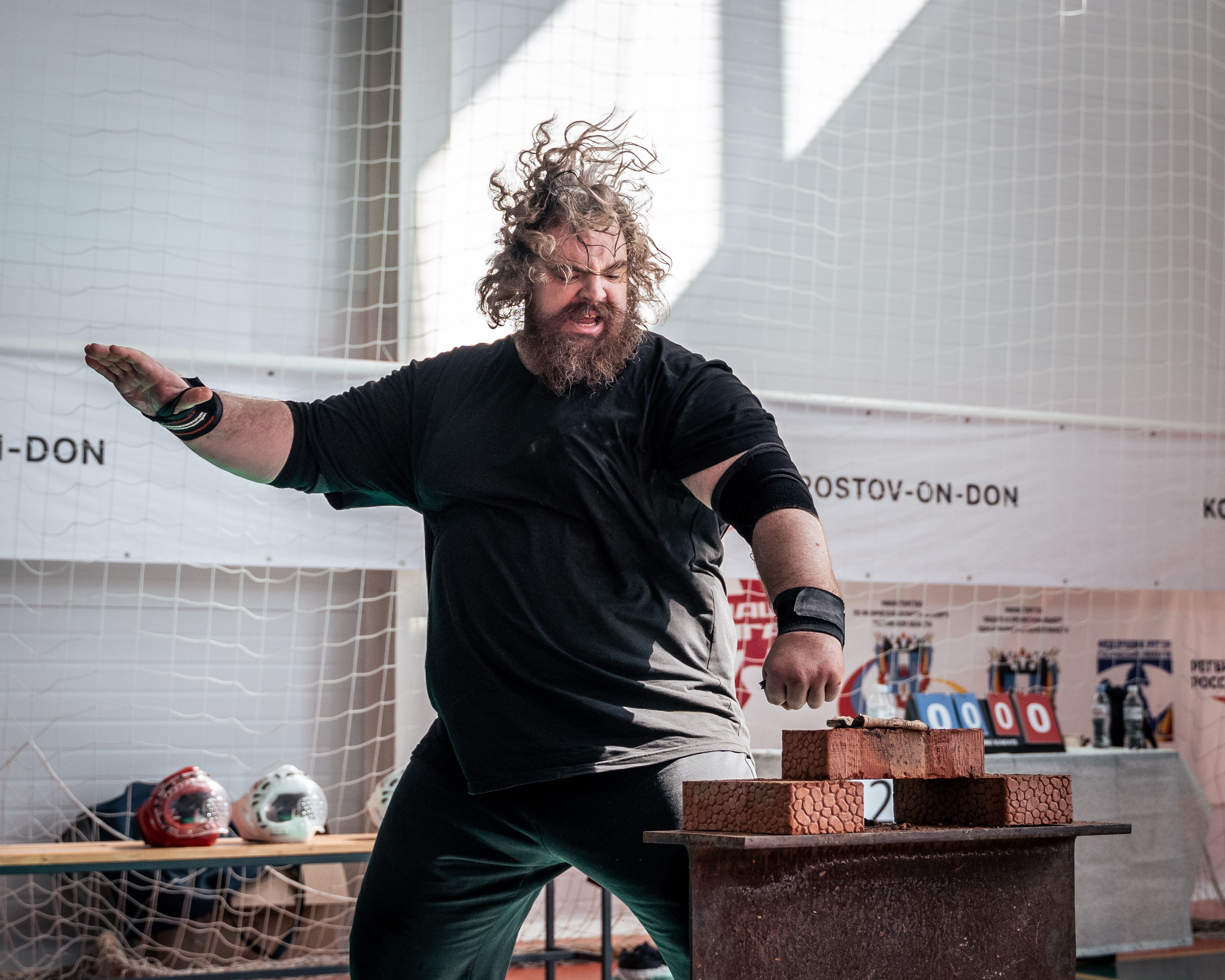 Dynamic image of a martial artist breaking bricks indoors, showcasing strength and skill.