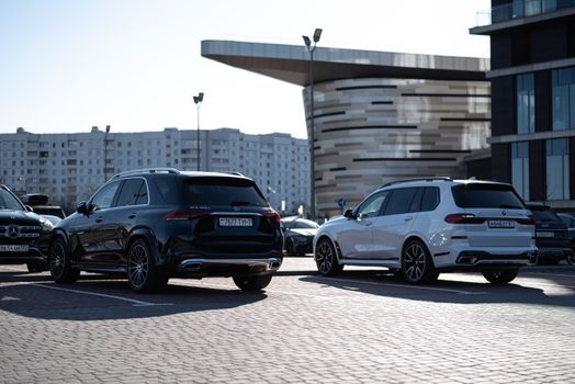 Two luxury SUVs parked in an urban setting with modern buildings in the background.