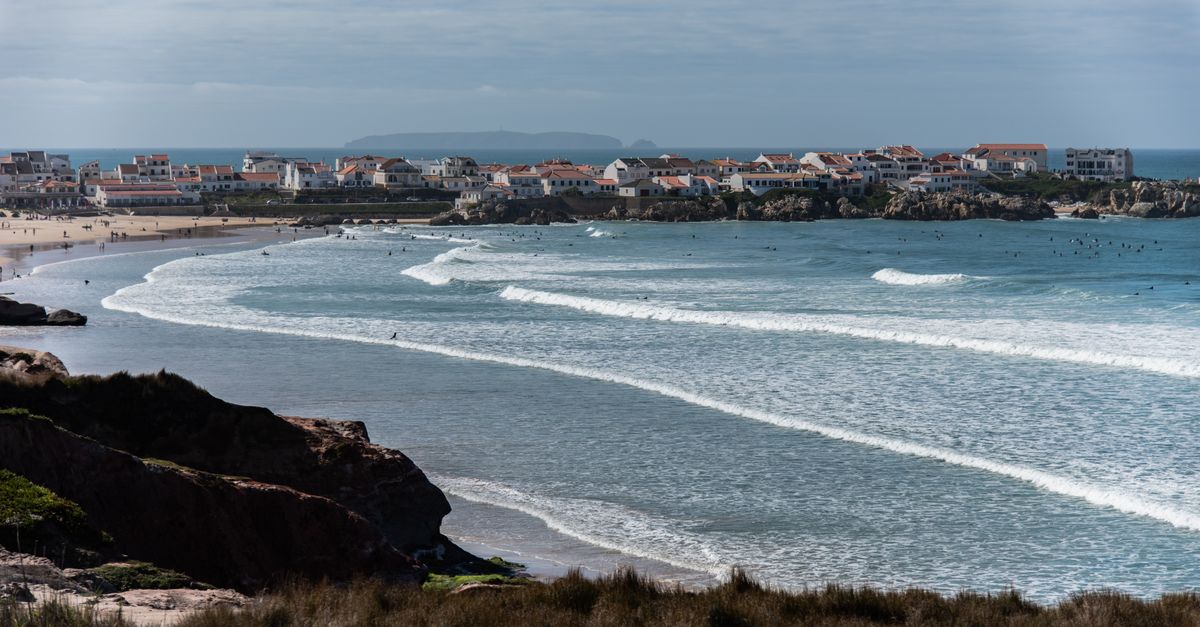 Picturesque view of Peniche's coastline with waves crashing and houses by the Atlantic.