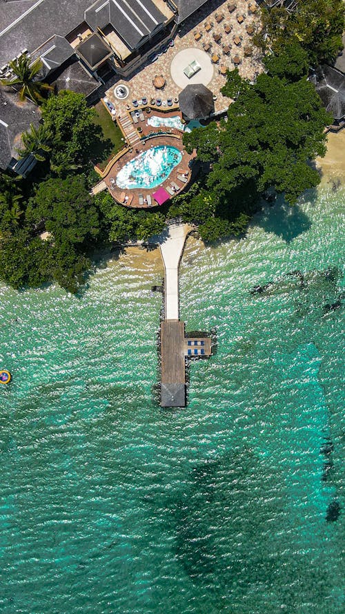 Top View of a Resort with a Swimming Pool and a Pier on the Seashore 