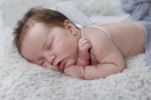 Free A peaceful baby with angel wings sleeping on a soft blanket, capturing innocence. Stock Photo