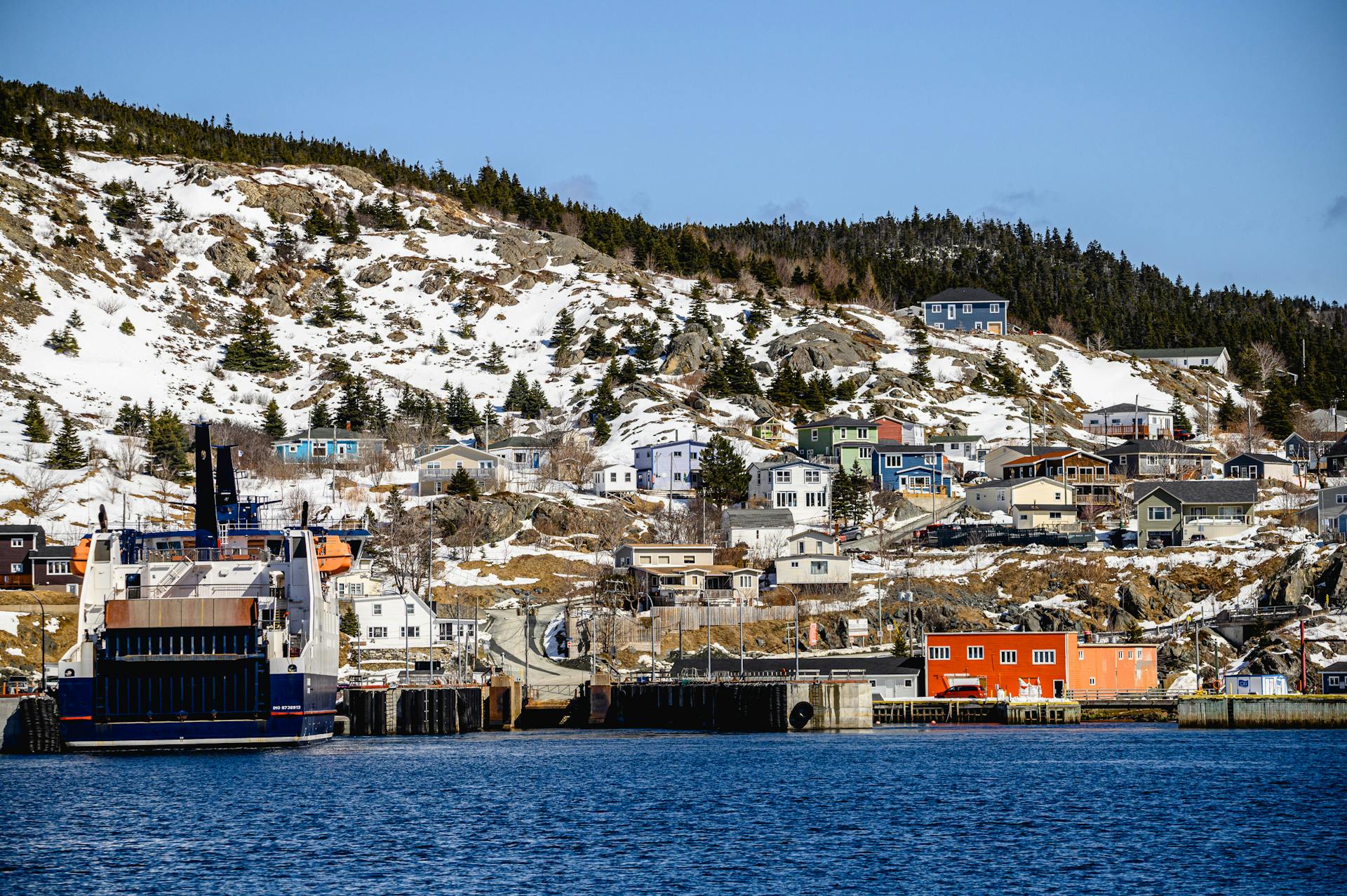 Snow-covered coastal village of Portugal Cove-St. Philip's, Canada, with a ferry docked at the harbor.