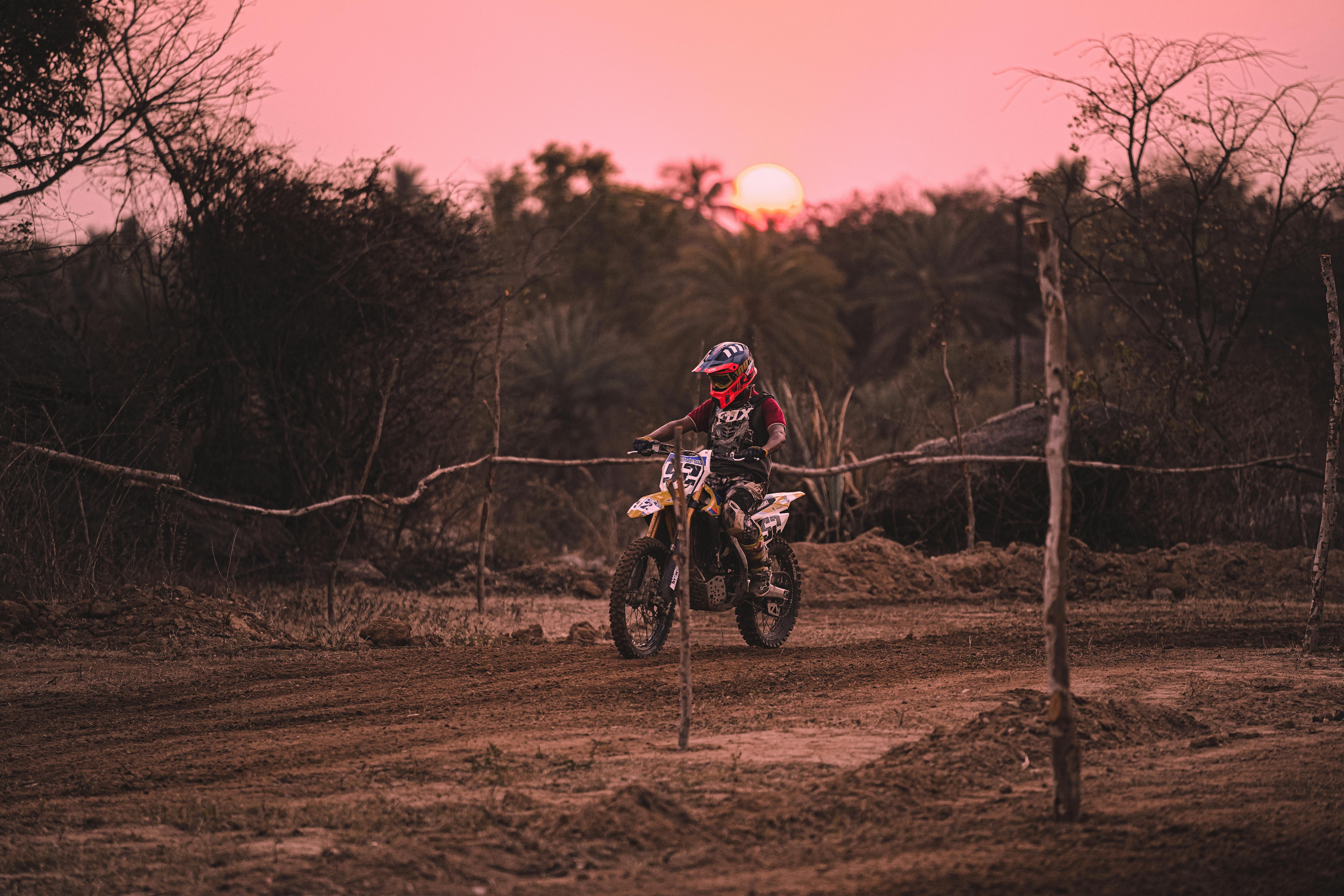 A motocross rider on a dirt track at sunset, showcasing motorsport adventure.