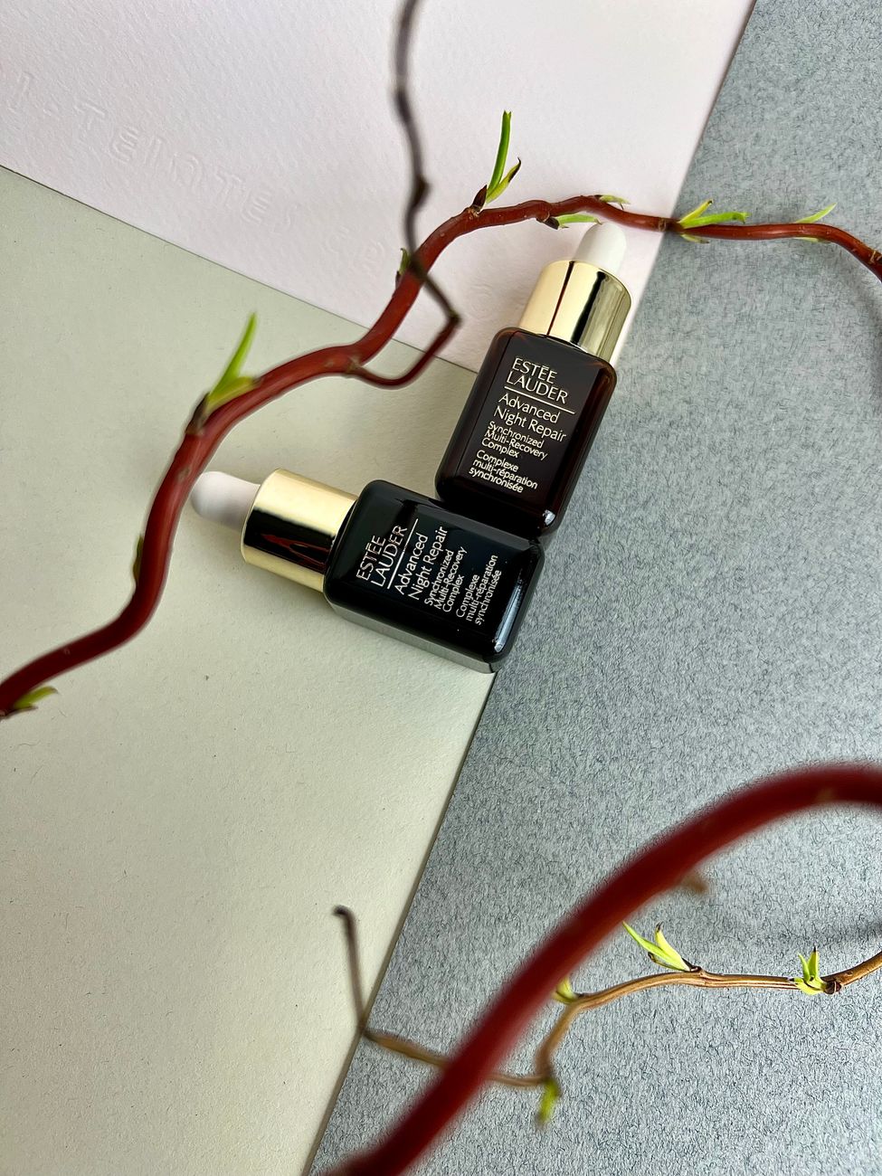 Elegant composition of skincare serum bottles intertwined with sprouting twigs for a natural touch.